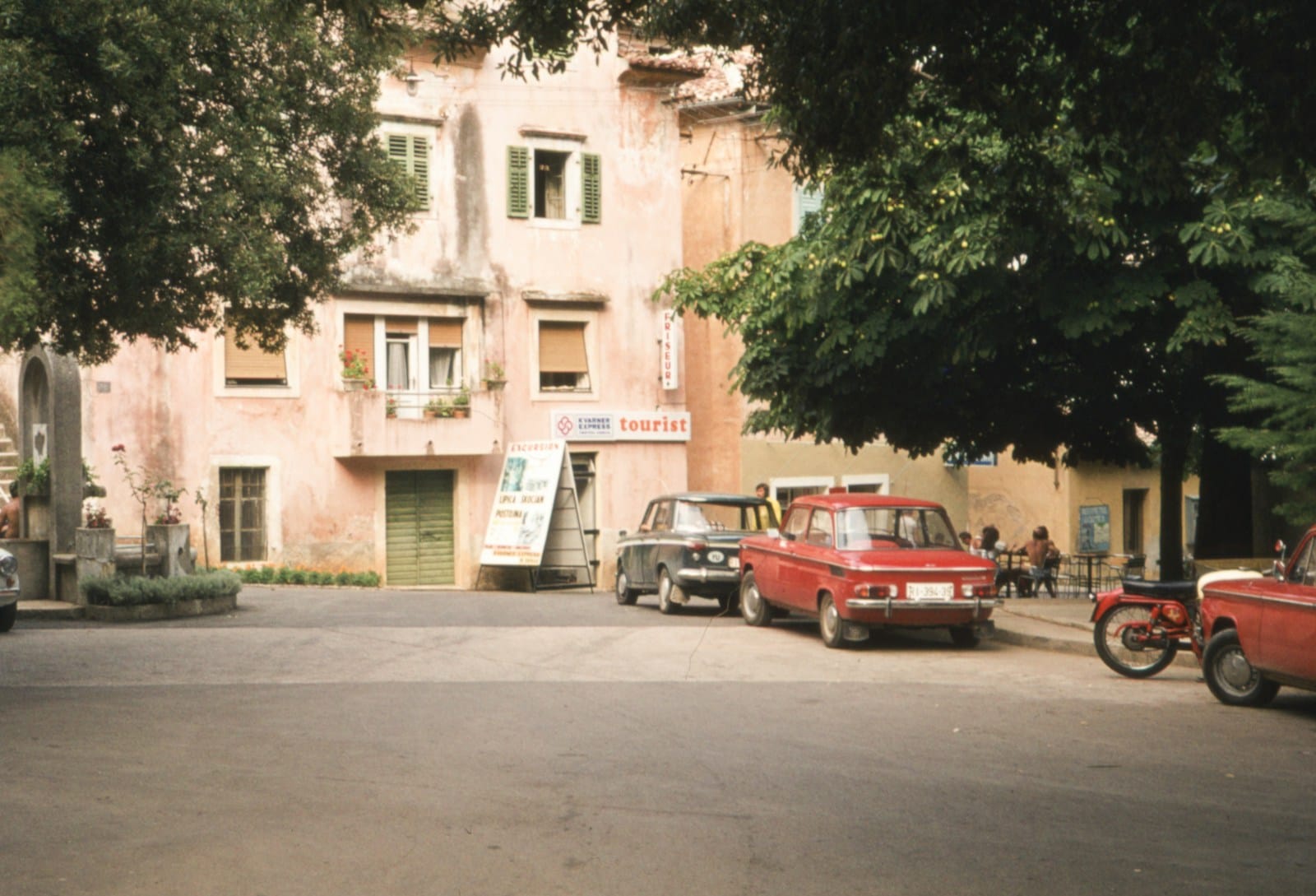 a red car parked in front of a tall building